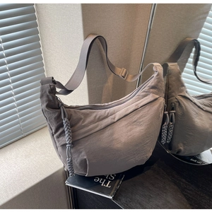 Detail of taupe nylon crescent bag with adjustable strap and braided zip pullers