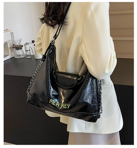 Dettaglio della borsa tote nera lucida con logo giallo neon e tracolla a catena in metallo