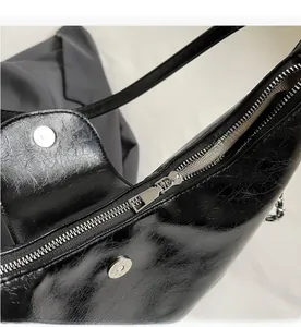 Dettaglio della borsa tote nera con trama cerata, zip metallica e chiusura magnetica
