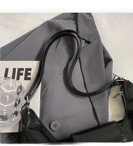 Dettaglio della borsa tote in pelle verniciata nera lucida con cerniera argentata e manico