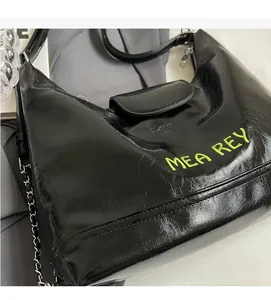 Dettaglio borsa in pelle oleata nera con logo MEA REY ricamato in verde e catena d'argento