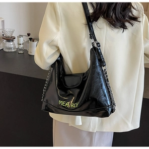 Dettaglio della borsa hobo nera lucida con scritte verde neon e tracolla a catena