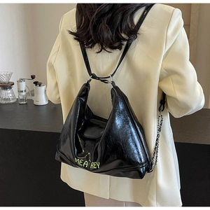 Dettaglio della borsa tote in pelle cerata nera con logo verde e catena d'argento