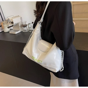 Dettaglio borsa hobo bianca con scritte verdi, catena argento e pelle testurizzata