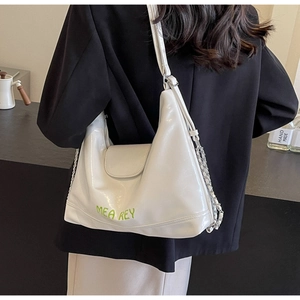 Dettaglio borsa hobo in pelle bianca con scritta MEA REY verde e tracolla a catena