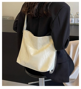 Detail of off-white wrinkled texture tote bag with wide strap and silver chain accents