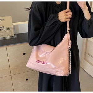 Dettaglio della borsa tote in vernice rosa con finitura lucida e catena sulla modella