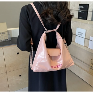 Borsa tote in pelle lucida rosa con catena argentata indossata da una modella