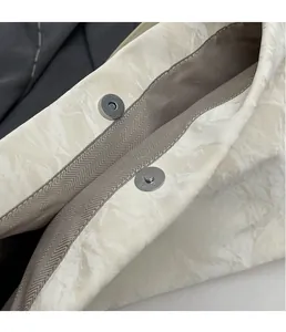 Macro detail of silver magnetic snap closure and textured nylon fabric on tote bag