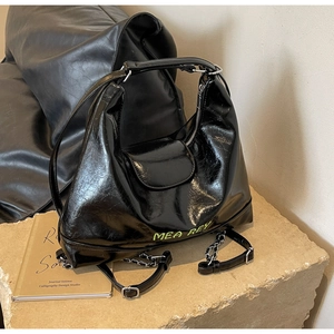 Dettaglio borsa in pelle nera lucida stropicciata con logo verde neon e catena