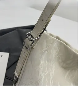 Close-up of shiny silver adjustable metal buckle and textured white leather shoulder strap