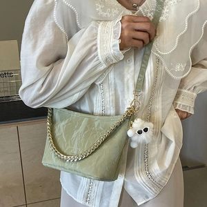 Light green bucket bag with wrinkled texture, gold chain and plush toy on model