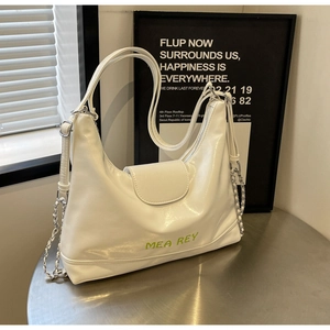 Dettaglio della borsa tote in pelle bianca lucida con scritte verde neon e catene argento