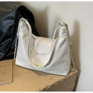 Dettaglio della borsa tote bianca lucida con testo MISA REY verde e catena d'argento
