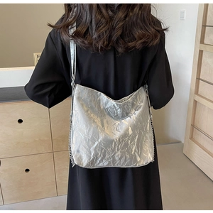 Detail of silver metallic tote bag with chain strap shown on a model's shoulder