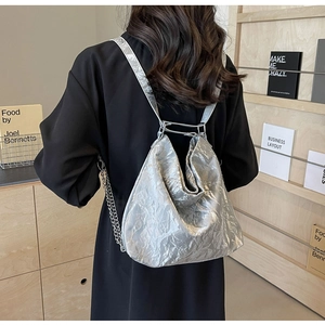 Detailed view of a silver backpack with metallic texture worn over the shoulder
