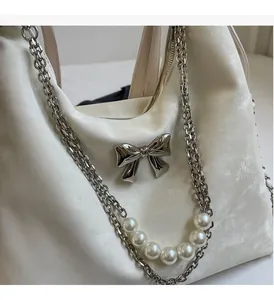Gros plan sur le satin crème brillant avec nœud en argent et chaîne de perles luxueuse