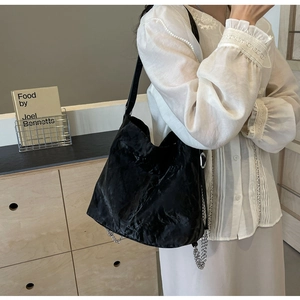 Detail of black wrinkled hobo bag with silver chain strap shown on a model