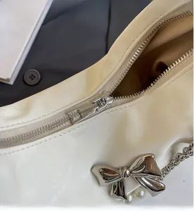 Détail de la fermeture éclair fluide et du nœud argenté sur le sac fourre-tout crème