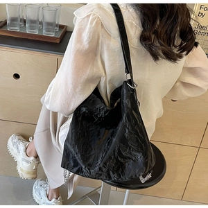 Detail of crinkled black tote bag with silver chain accents and wide shoulder strap