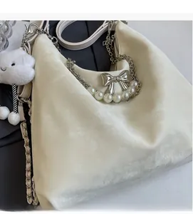 Détail du cabas en daim crème avec chaîne de perles et breloque nuage doux