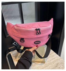 Dettaglio del borsello da petto in nylon rosa acceso con cerniere nere