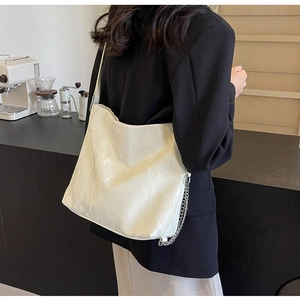 Side view of large cream tote bag with silver chain detail on a shoulder strap