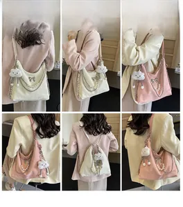 Détail montrant la chaîne de perles et le nœud sur le sac fourre-tout rose et blanc