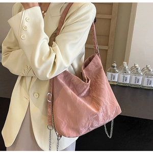 Close-up of pink pleated tote bag with silver chain details and textured fabric finish