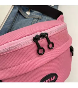 Dettaglio della borsa da petto in tela rosa con tessuto a coste e doppie cerniere in metallo