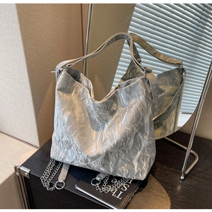 Detail of silver metallic tote bag featuring pleated texture and decorative metal chains