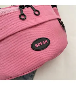Dettaglio del borsello rosa in tela con trama a costine verticali e logo BUFAN in gomma