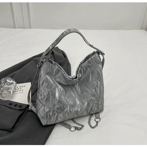 Detail of silver metallic wrinkled texture and chain strap on a large tote bag