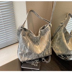 Detailed macro view of silver metallic crinkled texture tote with metal chain link details