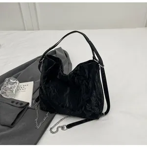 Close-up of black pleated tote bag with silver chain strap and wide leather handle