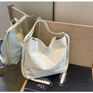 Detail of cream tote bag featuring pleated leather texture and silver chain strap