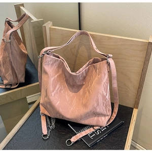 Detail view of pink tote bag with textured crinkle fabric and silver metal chain strap