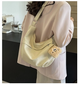 Detail of off-white dumpling bag with pleated texture and brown plush pendant