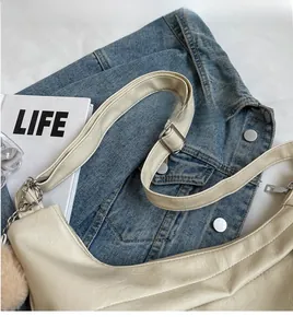 Detail view of cream crescent bag with lychee grain texture and chain strap