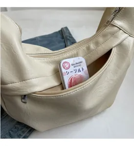 Detail view of large beige crescent bag with functional front zipper pocket and ample storage