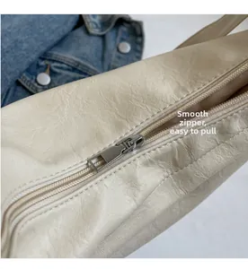 Detail of smooth silver metal zipper on beige pebbled leather large crossbody bag