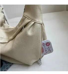 Detail of hobo bag side zipper pocket showing internal capacity and lychee leather texture