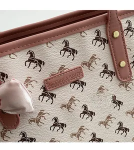 Detail of horse print tote bag featuring pink leather trim and golden metal rivet studs