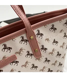 Detail of pink leather handles and gold rivets on a cream tote bag with horse pattern