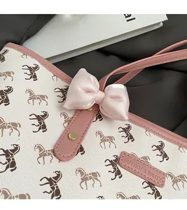 Detail of white tote bag with horse pattern, pink satin bow and golden hardware