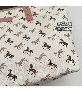 Detail of white lychee leather tote bag with horse prints and pink leather trim accents