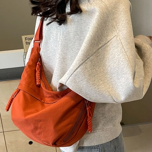 Orange nylon crescent crossbody bag with woven zipper and adjustable shoulder strap