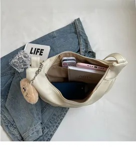 Top view showing spacious interior of the cream shoulder bag with books and phone