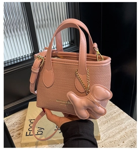 Borsa a secchiello rosa con trama intrecciata, ciondolo a cane e tracolla rimovibile