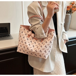 Detail of light pink tote bag with horse print and elegant bow decoration on the desk